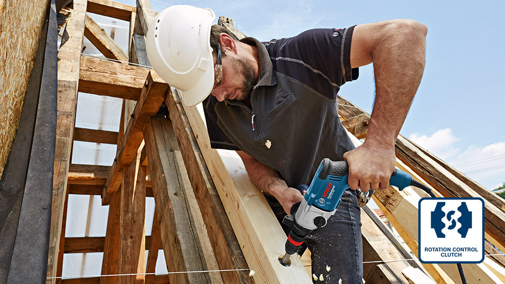 Rotation Control Clutch A man in a helmet uses a Bosch drill on wooden beams at a construction site.