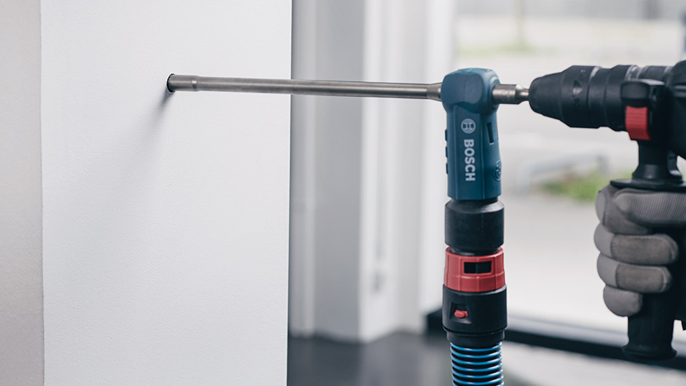 SpeedClean A Bosch Professional drill is fixing a screw into a white wall indoors.