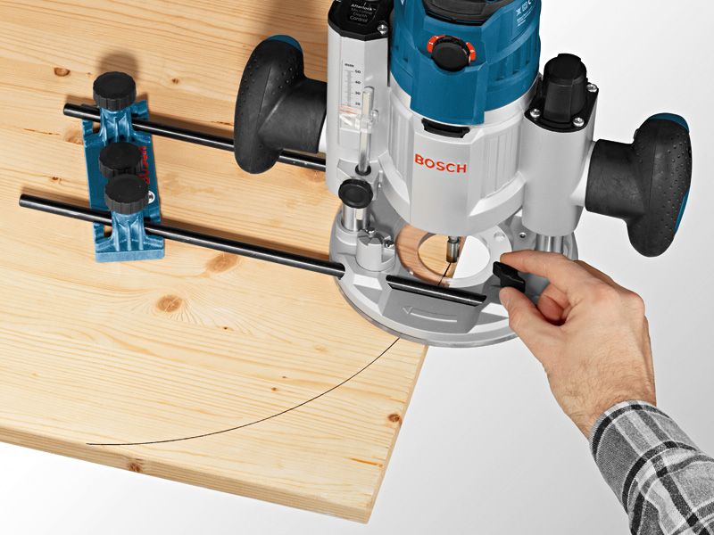 A person guides a plunge router along a curved line on a wooden board using a system accessory.