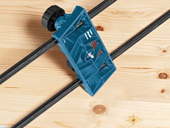 Drill guide system accessory clamped onto a wooden board.