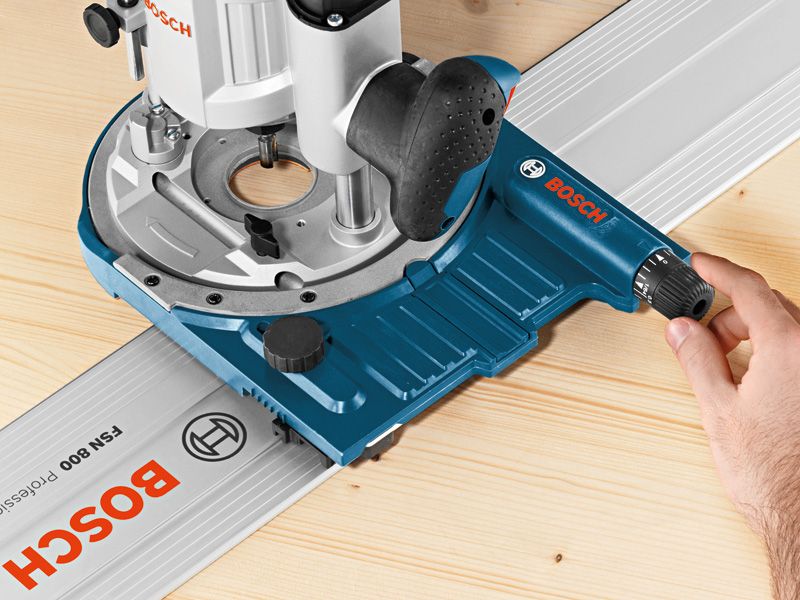 A person adjusts a system accessory track guide on a wooden surface.