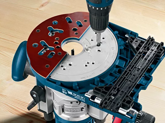 Drill driving a screw into a system accessory base plate on a router tool.