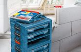 Stacked blue toolboxes with an open organizer tray holding screws and wall plugs nearby.