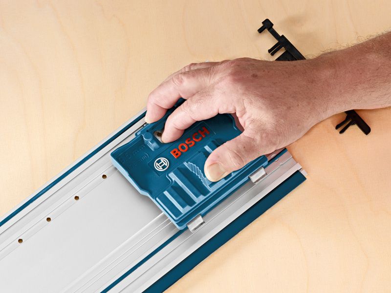 A person uses a blue system accessory on a metal rail set on a wooden surface.