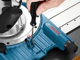A person adjusts a blue system accessory with a screwdriver on a metal guide rail.
