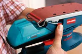 A person attaches sandpaper to an orbital sander.
