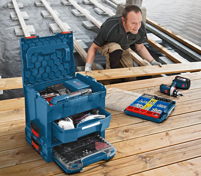A person wearing safety equipment installs wooden planks beside an open tool organizer.