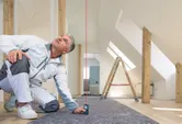 Person in work clothes uses a laser measure to check vertical distance in a renovated room.