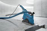 Wall chaser with dust extraction hose cutting a straight groove in a concrete floor.