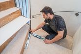 A person measures the angle of a staircase using an angle measurer.