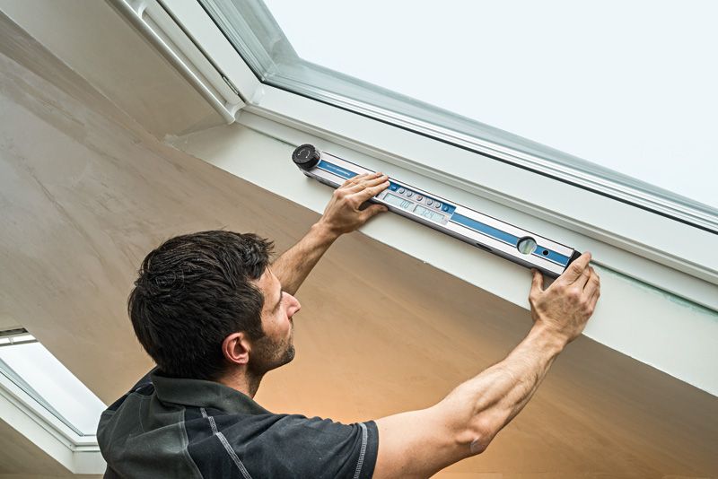A person measures the angle of a window frame using an angle measurer.