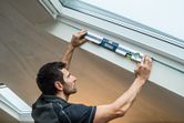 Person holding a digital inclinometer to measure the angle of a sloped ceiling.
