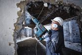 Worker drilling concrete wall.