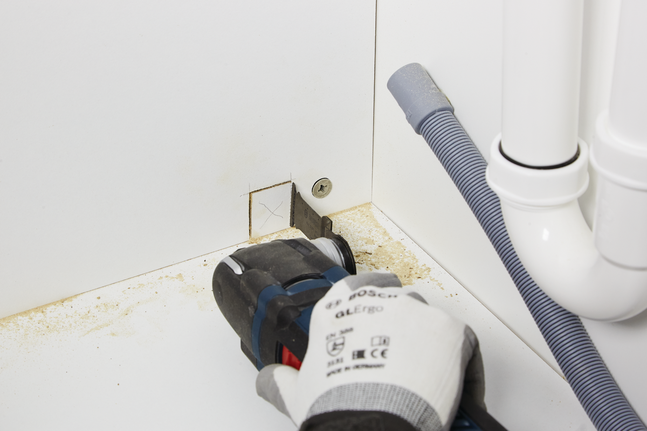 HCS plunge cut saw blade AIZ 32 EPC Wood Worker wearing safety equipment cuts a square opening in a cabinet with a power tool.