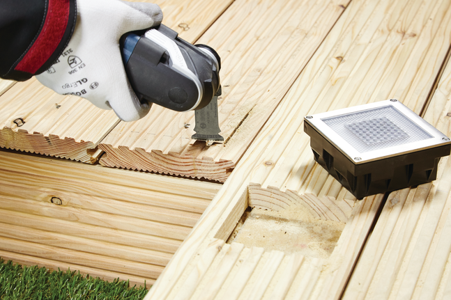 HCS plunge cut saw blade AIZ 32 EPC Wood Worker wearing safety equipment cuts a groove in a wooden deck using a multi-tool.