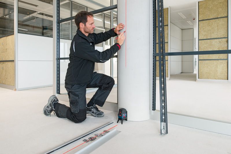 GCL 2-15 A person in workwear marks a pillar using a laser leveling tool.
