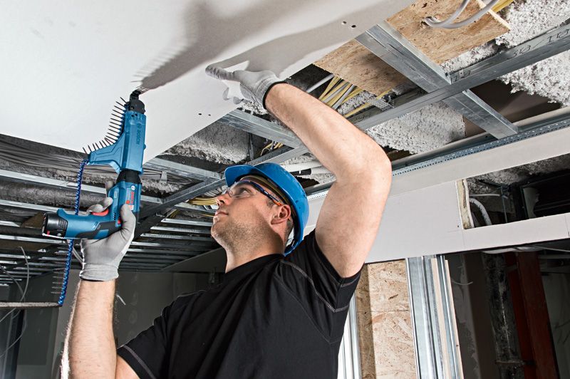 GTB 12V-11 A person wearing safety equipment fastens drywall to a ceiling using a cordless screwdriver.