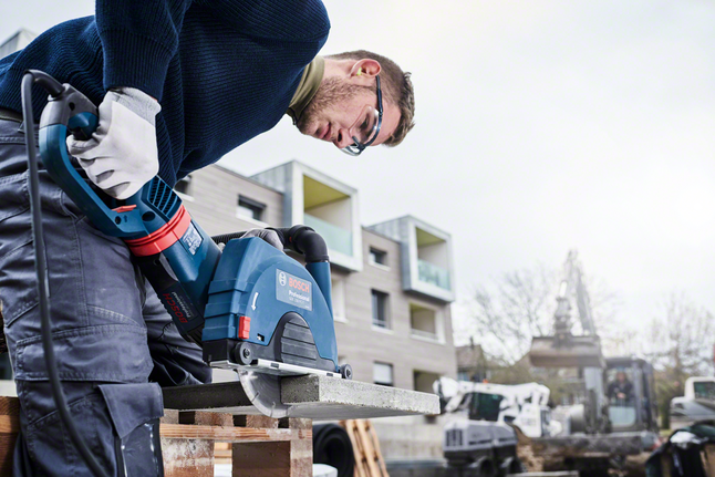 Standard for Stone diamond cutting disc Person wearing safety equipment uses a power saw to cut a concrete slab outdoors.