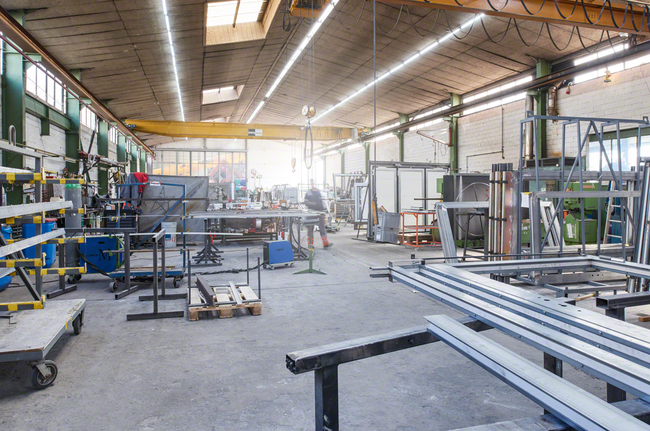 HSS Twist Drill Bit PointTeQ 18pcs ToughBox Set 1 - 10 mm Worker wearing safety equipment moves through a metal fabrication workshop.
