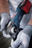 A person wearing safety equipment attaches a cutting blade to a cordless power tool.