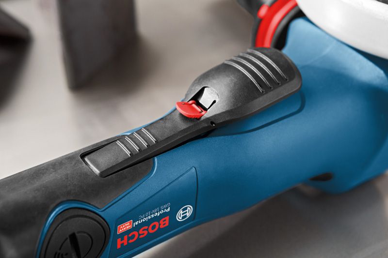 Close-up of a power tool handle with a textured black grip and red safety switch.