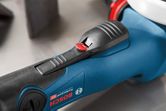 Close-up of a power tool handle with a textured black grip and red safety switch.
