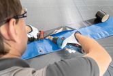 A person wearing safety equipment seals a plastic sheet with a heat gun.