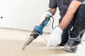 A person wearing safety equipment uses a heat gun to weld flooring material.
