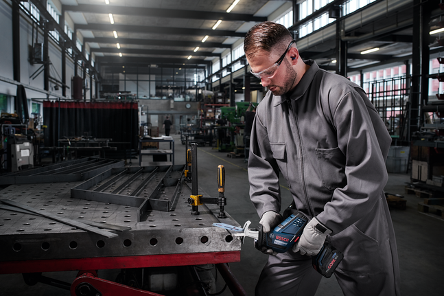 Reciprocating saw blade S 123 XF Person wearing safety equipment cuts metal on a workbench with a cordless saw.