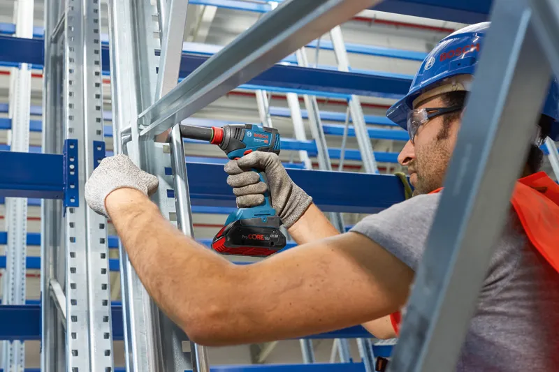 GDX 18V-200 A person wearing safety equipment uses a cordless drill on a metal frame.