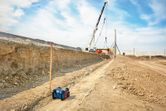 Laser leveling tool set on a construction site with a crane lifting materials in the background.