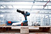 Cordless impact wrench on a wooden pallet with bolts at a construction site.