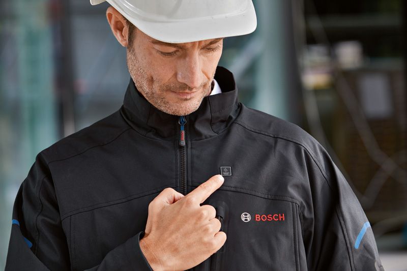 Person wearing safety equipment activates a heated jacket by pressing the chest button.