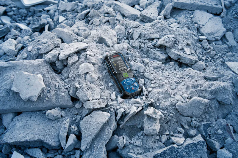 GLM 50-23 G Laser measure device resting on a pile of broken concrete rubble.