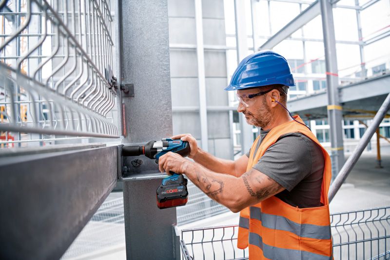 GDS 18V-1000 C A person wearing safety equipment uses a cordless impact wrench on a steel beam.