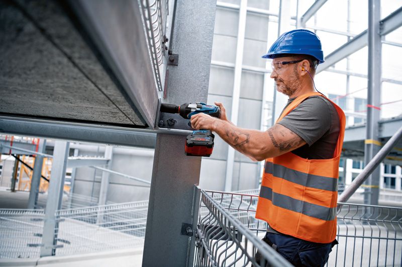 GDS 18V-1000 C A person wearing safety equipment uses a cordless impact wrench on a steel beam.