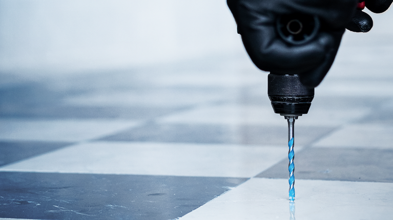 EXPERT HEX-9 MultiConstruction Drill Bit Set 5/6/8 mm 3-pc Person wearing safety equipment drills into a tiled floor.