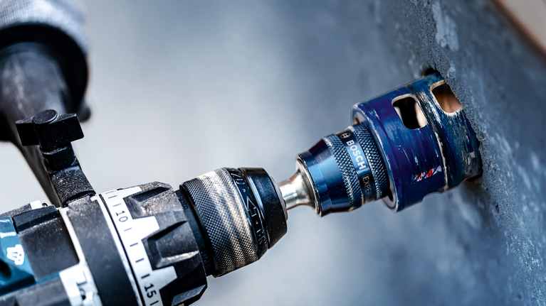 EXPERT Power Change Plus Hole Saw System Arbor 11 mm, HSS-G Drill 7.15 x 105 mm, 2-pc Drill with a hole saw attachment making a circular cut in a concrete wall.