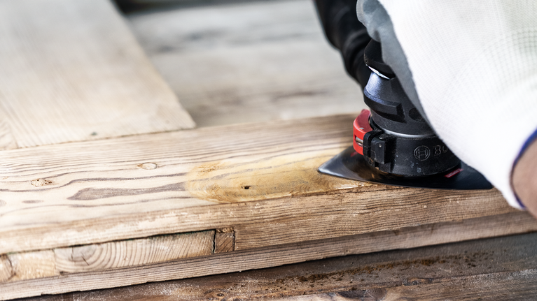 EXPERT Sanding Plate AVZ 90 RT10 Multitool Blade 90 mm Person wearing safety equipment sands a wooden board with a power tool.