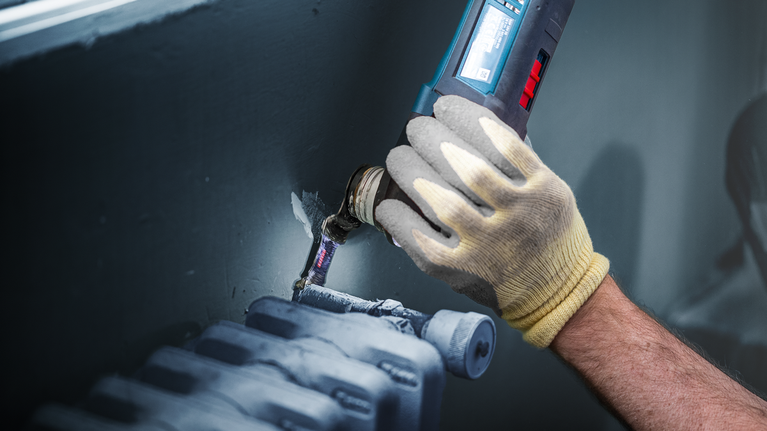 EXPERT MetalMax AIZ 45 AIT Multitool Blade 45 mm Person wearing safety equipment uses a power tool to cut around a pipe near a radiator.