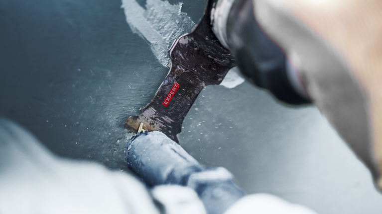 EXPERT MetalMax AIZ 45 AIT Multitool Blade 45 mm Person cutting through a painted metal pipe with a reciprocating saw blade.