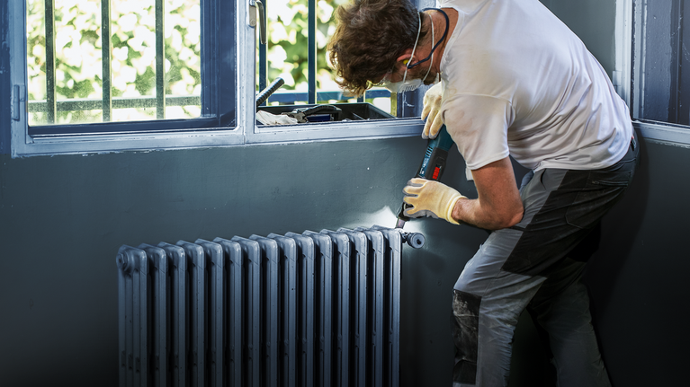 EXPERT MetalMax PAIZ 32 AIT Multitool Blade 50 x 32 mm Person wearing safety equipment uses a cordless drill to install a radiator.