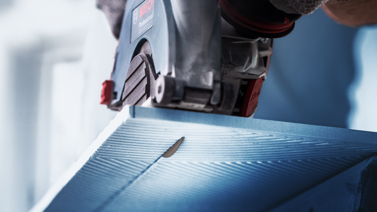 EXPERT HardCeramic X-LOCK Diamond Cutting Disc 115 x 22.23 x 1.4 x 10 mm Person wearing safety equipment cuts a blue panel with a circular saw.