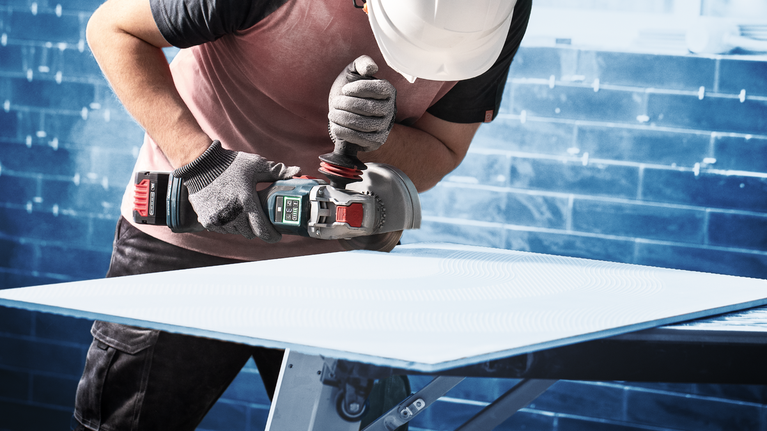 EXPERT HardCeramic X-LOCK Diamond Cutting Disc 115 x 22.23 x 1.4 x 10 mm Person wearing safety equipment grinds a sheet material on a workbench.