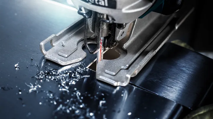 Object #200360681: 2793292_web_001 Jigsaw cutting a precise hole in a sheet of metal, surrounded by metal shavings.