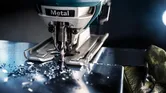 Person wearing safety equipment guides a jigsaw cutting through a metal sheet.