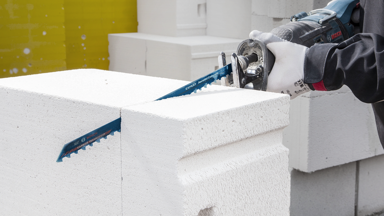 EXPERT ‘Aerated Concrete’ S 1141 HM Reciprocating Saw Blade 1-pc Person wearing safety equipment cuts a white concrete block with a reciprocating saw.