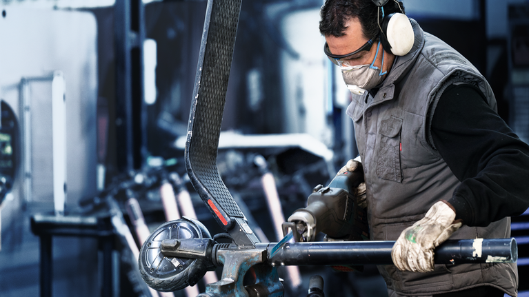 EXPERT ‘Medium-Thick Tough Metal’ S 955 HHM Reciprocating Saw Blade 1-pc A person wearing safety equipment grinds a metal pipe in an industrial workshop.