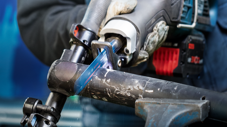 EXPERT ‘Medium-Thick Tough Metal’ S 1155 HHM Reciprocating Saw Blade 1-pc Person wearing safety equipment uses a reciprocating saw to cut a metal pipe.
