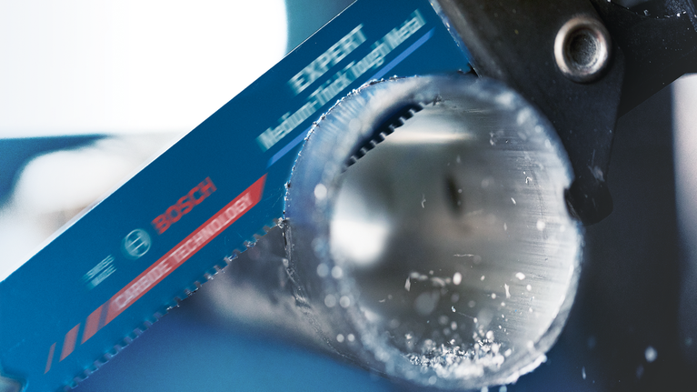 EXPERT ‘Medium-Thick Tough Metal’ S 955 HHM Reciprocating Saw Blade 1-pc Saw blade cutting through a metal pipe with metal shavings visible.
